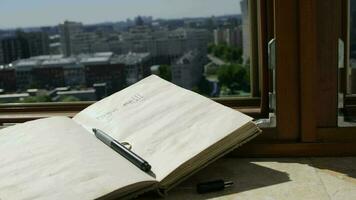 journal intime avec une stylo à marbre seuil de un ouvert la fenêtre. soufflant gris transparent rideaux video