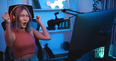 asiático joven deporte mujer jugador sensación bueno cuando victorioso jugar en línea juego en ordenador personal foto