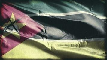 retro envelhecido Moçambique bandeira acenando em a vento. velho vintage moçambicano bandeira balançando em a brisa. desatado laço. video