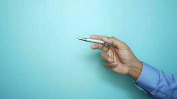 Hand holds a pen against blue background video