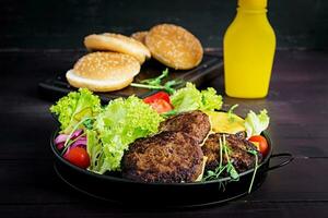 Burger cooking - burger with beef,  tomato, cheese, pickled cucumber and red onion on plate photo