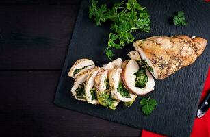 Roasted sliced Christmas roll of turkey with spinach and cheese on dark rustic background. Top view, copy space. Festival food. photo