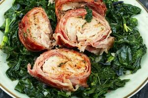 Sliced chicken roll and fried spinach. photo