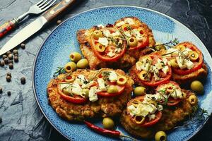 Schnitzel with olives and tomato photo