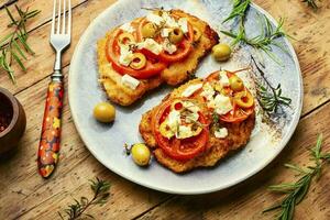 Fried schnitzel with olives and tomato photo