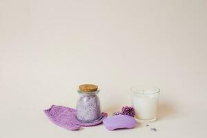 Spa care with natural soap, sea salt, washcloth glove for body care, lilac flowers and a candle on a light background with copy space photo