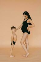 Happy motherhood. A pregnant woman in the studio on a beige background with her five-year-old son, measuring the size of their bellies photo