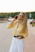 Happy young woman smiling and walking in the street talking on a smartphone photo