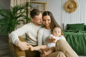 mamá, papá y seis meses de edad bebé hijo en su brazos gastar hora juntos en su acogedor hogar foto