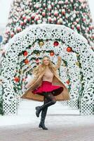 un joven elegante mujer es teniendo divertido y tripulación un festivo Navidad mercado en el antecedentes. el modelo es vestido en un elegante invierno Saco y un borgoña falda foto