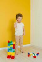 Child is playing with colorful cubes at the table. Kid has fun and builds from bright construction blocks. Early learning. Educational toys photo