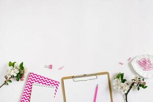 elegante plano laico De las mujeres lugar de trabajo con cuadernos, tableta, bolígrafo y primavera manzana flores en un blanco antecedentes con Copiar espacio foto