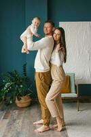 Happy young parents hold their little son in their arms and smile happily at the camera photo