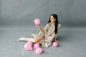 un imagen de un alegre mujer quien siente muy feliz, participación un rosado globo y reír, posando cerca globos foto