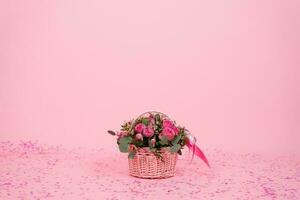 Beautiful bouquet of pink roses and eucalyptus branches in a gift basket on a pink background with confetti for birthday, Valentine's day or mom's day photo