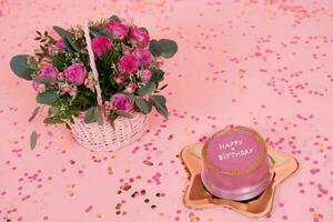 Trendy pink and gold festive Korean bento cake on a golden plate in the shape of a star on a pink background with confetti and a basket with fuchsia roses photo