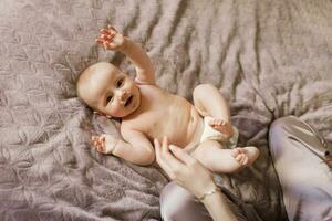 Cute baby in a diaper lying on the bed on his back photo