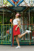 A beautiful young woman walks in an amusement park and holds a paper cup in her hands photo