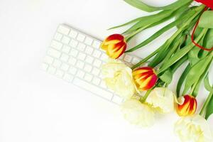 plano acostado San Valentín día antecedentes con computadora teclado y tulipán ramo. primavera parte superior vista. foto