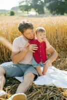 Father and his son have a rest outdoors in a field in summer photo