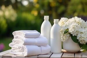 Laundry, housekeeping and homemaking, white clean folded clothes and detergent conditioner bottles in the garden, country cottage style, photo