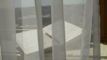 Tagebuch mit ein Stift beim Marmor Schwelle von ein öffnen Fenster. weht grau transparent Vorhänge video