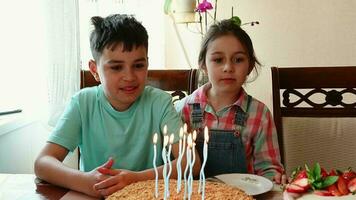 gut aussehend spanisch Teenager Junge feiert seine Geburtstag Party, weht aus Kerzen auf seine lecker festlich Kuchen während seine bezaubernd jünger Schwester Singen glücklich Geburtstag Lied. Kindheit. festlich Leben Veranstaltung video