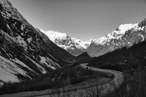 ver Entre montañas en Noruega, mediante cuales un la carretera Guías en negro blanco. foto