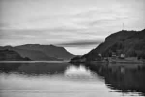Fjord with view of mountains and fjord landscape in Norway in black and white photo