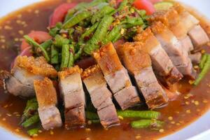 Stir fried crispy pork and green yardlong bean with red curry paste. photo