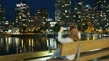 femme prend des photos de le grattes ciels de Vancouver sur sa téléphone intelligent à nuit video