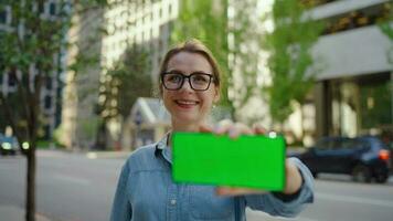 femme est montrant téléphone intelligent avec vert maquette écran à le caméra. video