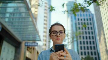 Caucasian woman in glasses walking around the city and using smartphone video