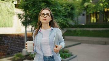 femme en marchant sur rue avec portable et café dans mains après travail journée video