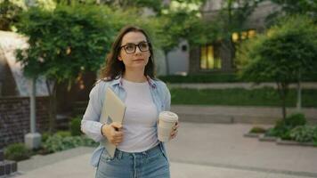 vrouw wandelen Aan straat met laptop en koffie in handen na werk dag video