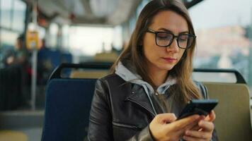 Public transport. Woman in glasses in tram using smartphone video