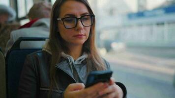 público transporte. mujer en lentes en tranvía utilizando teléfono inteligente, lento movimiento video