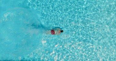 Aerial view as a man dives into the pool and swims, slow motion video