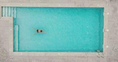 parte superior abajo ver de un hombre en rojo pantalones cortos nadando en el piscina, lento movimiento. video