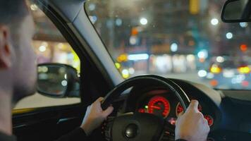 hombre conducción coche mediante el calles de noche ciudad. video