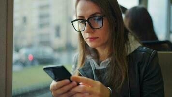 Public transport. Woman in glasses in tram using smartphone video