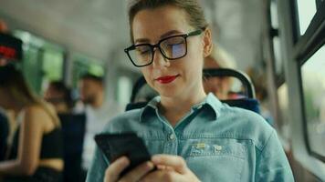 Publique transport. femme dans des lunettes dans tram en utilisant téléphone intelligent. video