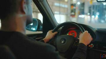 hombre conducción coche mediante el calles de noche ciudad. video