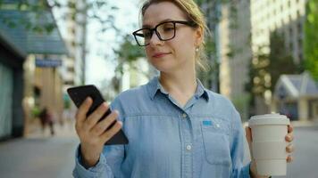 caucasico donna nel bicchieri sta su il strada e utilizzando smartphone video