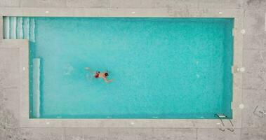 Top down view of a man in red shorts swimming in the pool, slow motion. video