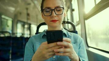 offentlig transport. kvinna i glasögon i spårvagn använder sig av smartphone. långsam rörelse video