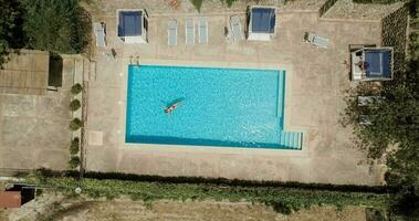 parte superior abajo ver de un mujer en rojo traje de baño acostado en su espalda en el piscina. video