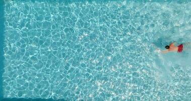 Top down view of a man in red shorts swimming in the pool, slow motion. video