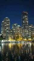 Visão em centro da cidade do Vancouver às noite. edifícios estão refletido dentro a água video