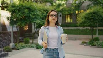 mujer caminando en calle con ordenador portátil y café en manos después trabajo día video